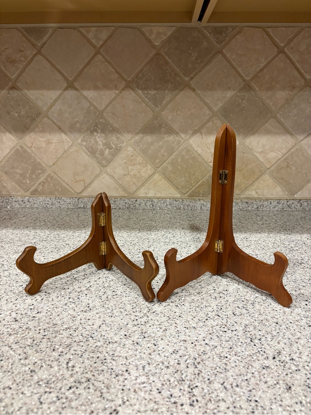 Two Walnut-finished wooden folding display easel stands brass-toned metal hinges